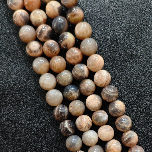 Macro closeup of natural black sunstone smooth round beads displaying metallic schiller sheen