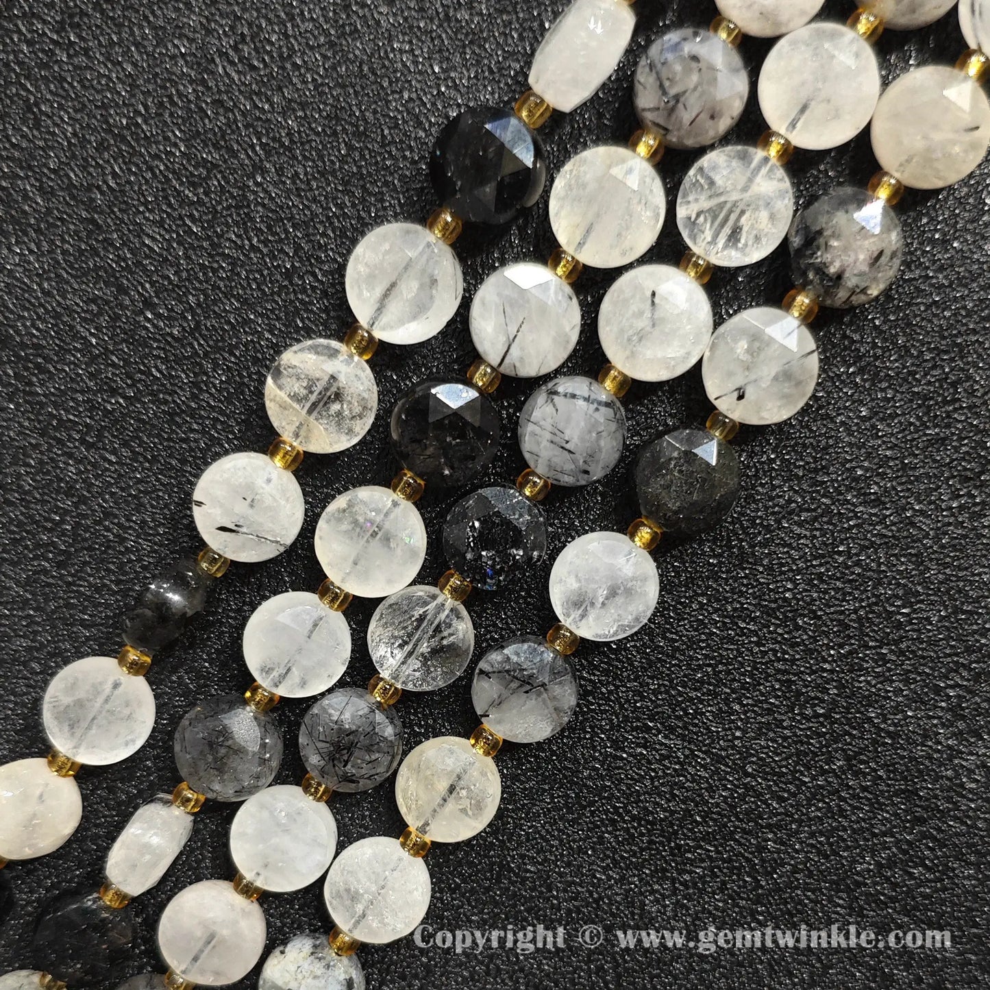 Close up view of black tourmalinated quartz faceted flat disc beads showing needle inclusions
