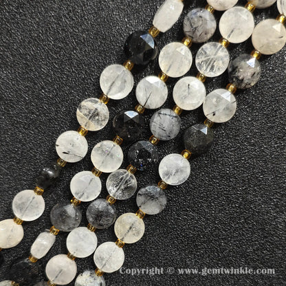 Close up view of black tourmalinated quartz faceted flat disc beads showing needle inclusions