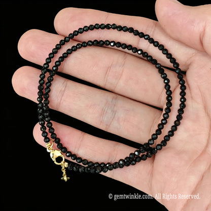 untreated black tourmaline faceted bead necklace loop with gold tone extender chain in hand
