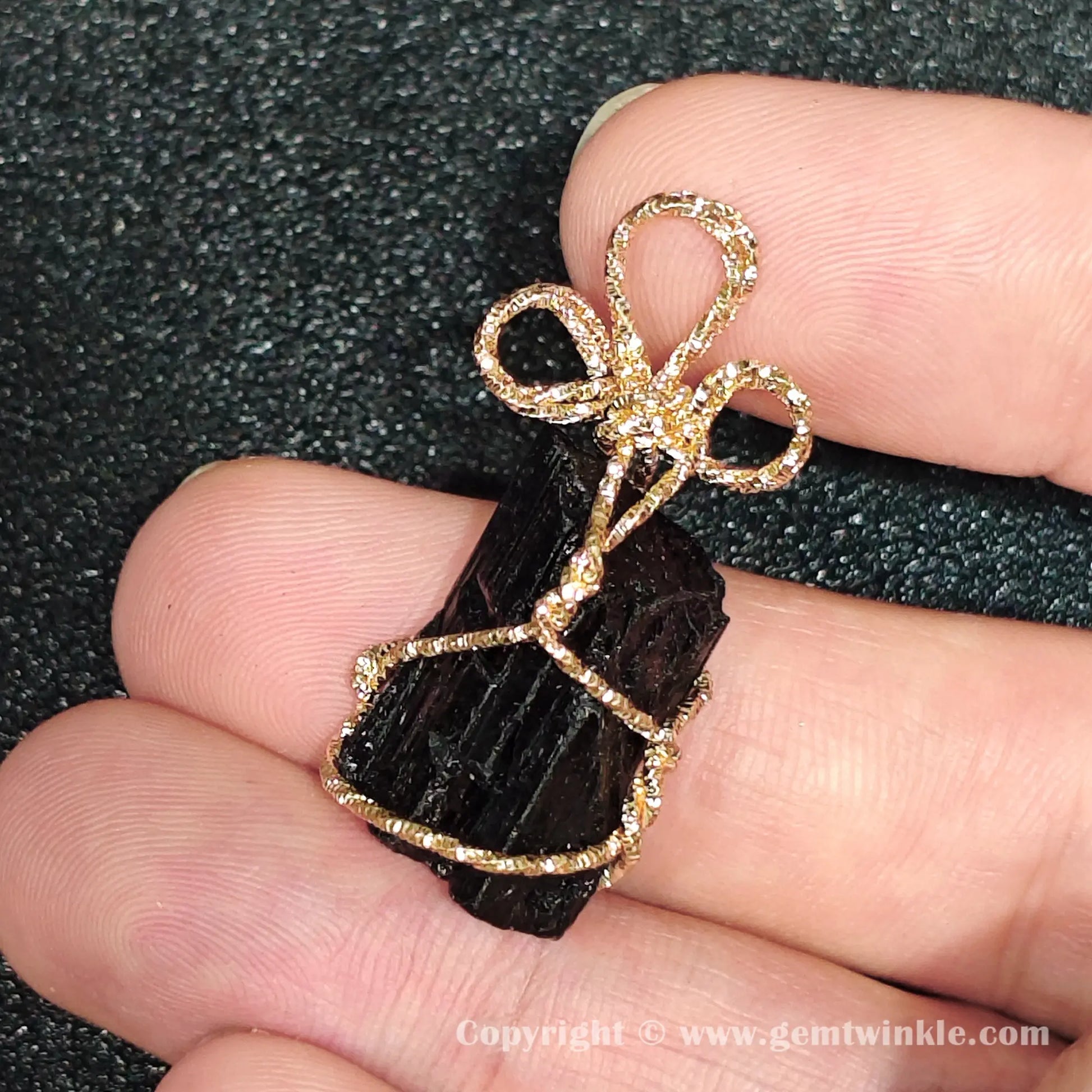 Side view of 3cm raw black tourmaline rough stone encased in gold-tone metal craft wire frame
