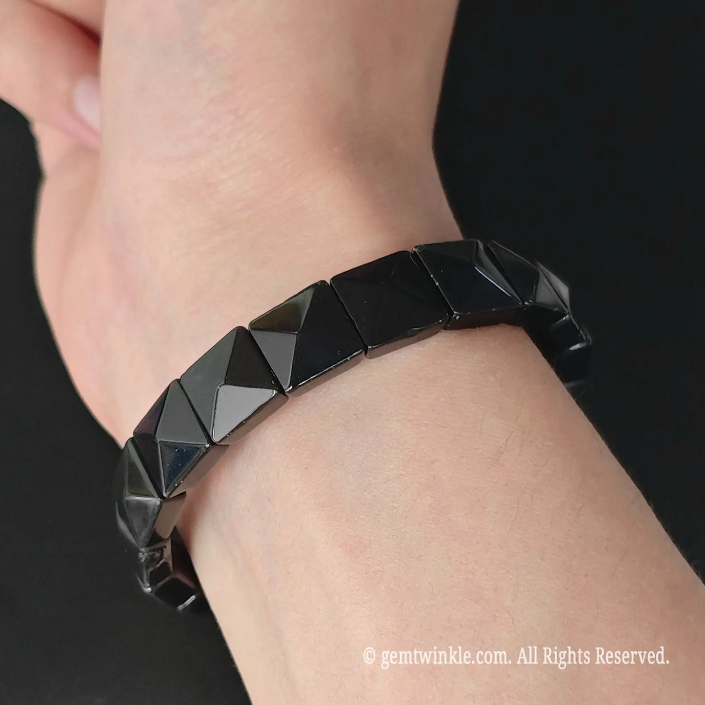 Black obsidian 11mm pyramid cut square bead stretch bracelet styled on wrist displaying lustrous black geometric sheen
