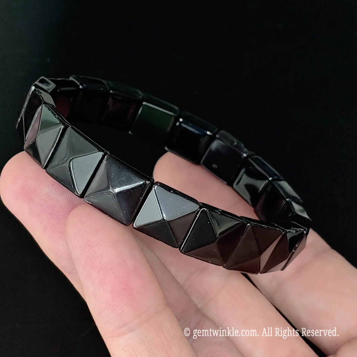 Black obsidian pyramid stud style square bead cuff bracelet displayed across fingers showing uniform bead alignment