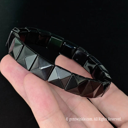 Black obsidian pyramid stud style square bead cuff bracelet displayed across fingers showing uniform bead alignment