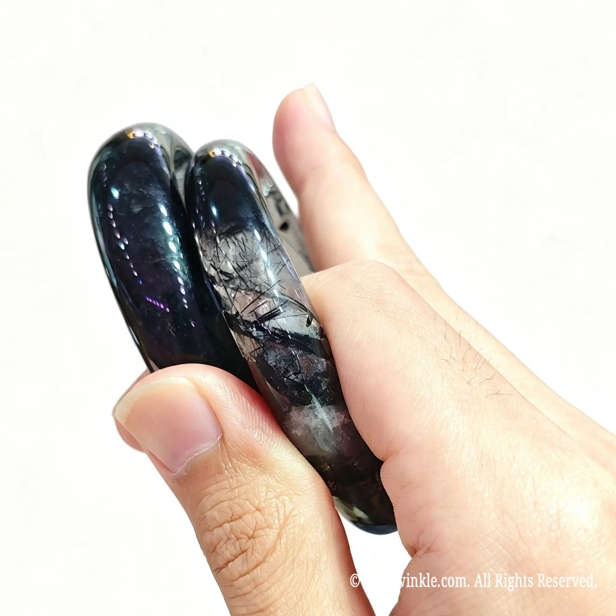 Dense black rutilated quartz bangle bracelet held in hand showing translucent clarity and dense rutile inclusions