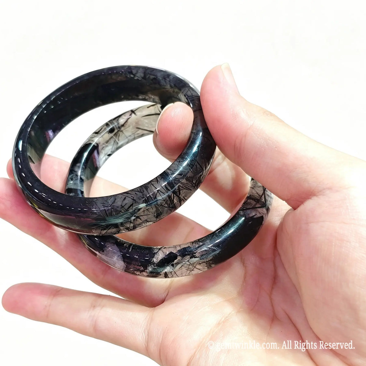 Close up view of black rutile gemstone band held in hand with clear quartz matrix and custom inner diameter fit