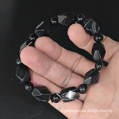 Angle view of black sardonyx 15mm faceted geometric bead bracelet highlighting light reflection across geometric facets