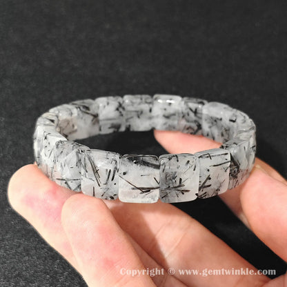 angled view of natural black rutilated quartz bangle plate bracelet displaying 16-17cm wrist fit