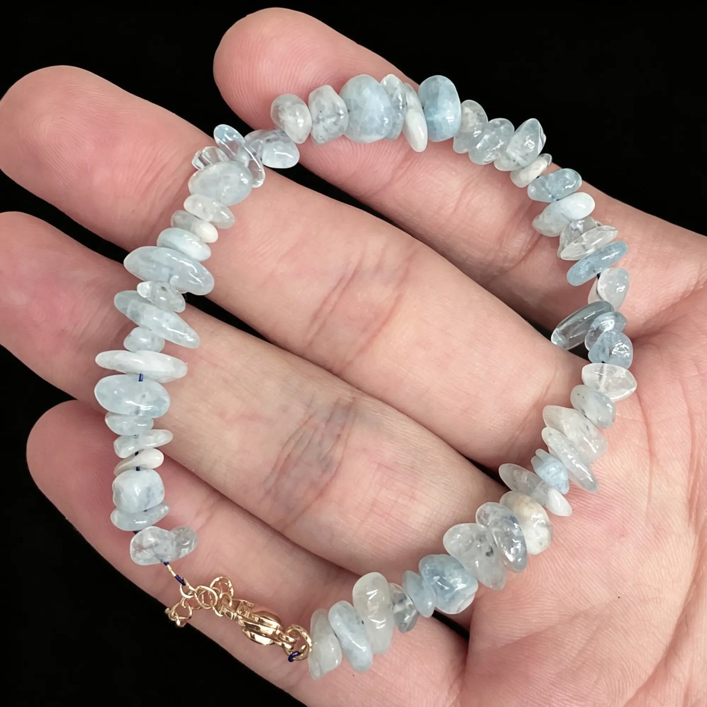 blue aquamarine raw nugget bracelet held on hand displaying natural icy tones