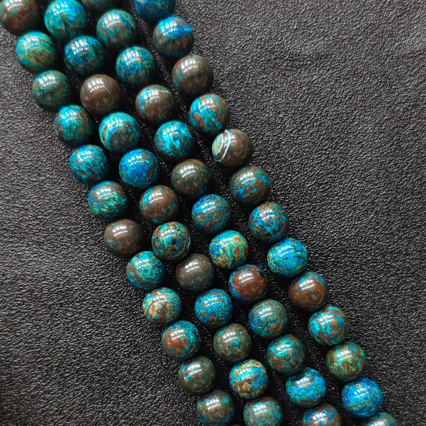 Macro closeup of blue chrysocolla phoenix stone smooth round beads showing vibrant peacock matrix