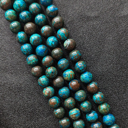 Macro closeup of blue chrysocolla phoenix stone smooth round beads showing vibrant peacock matrix