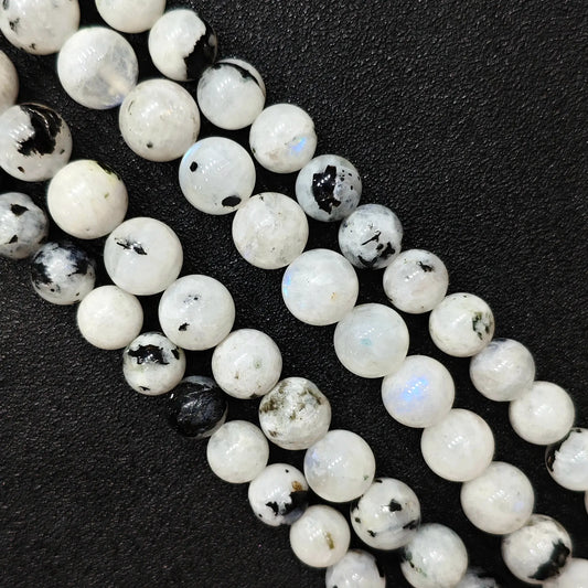 Macro closeup of blue flash moonstone round beads showing electric blue sheen and black tourmaline spots