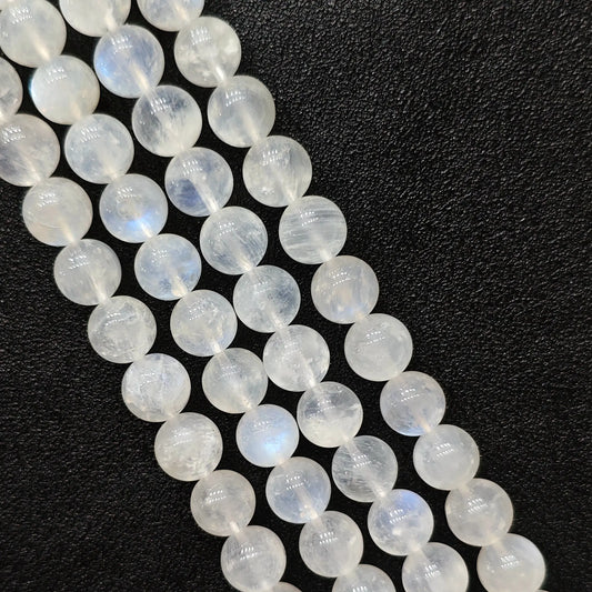 Macro closeup of blue flash moonstone smooth round beads showing natural internal ice fractures and blue sheen