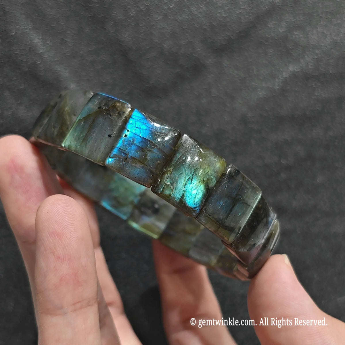 Side view of a blue flash labradorite bar cut bangle showcasing vibrant iridescent sheen across plate beads