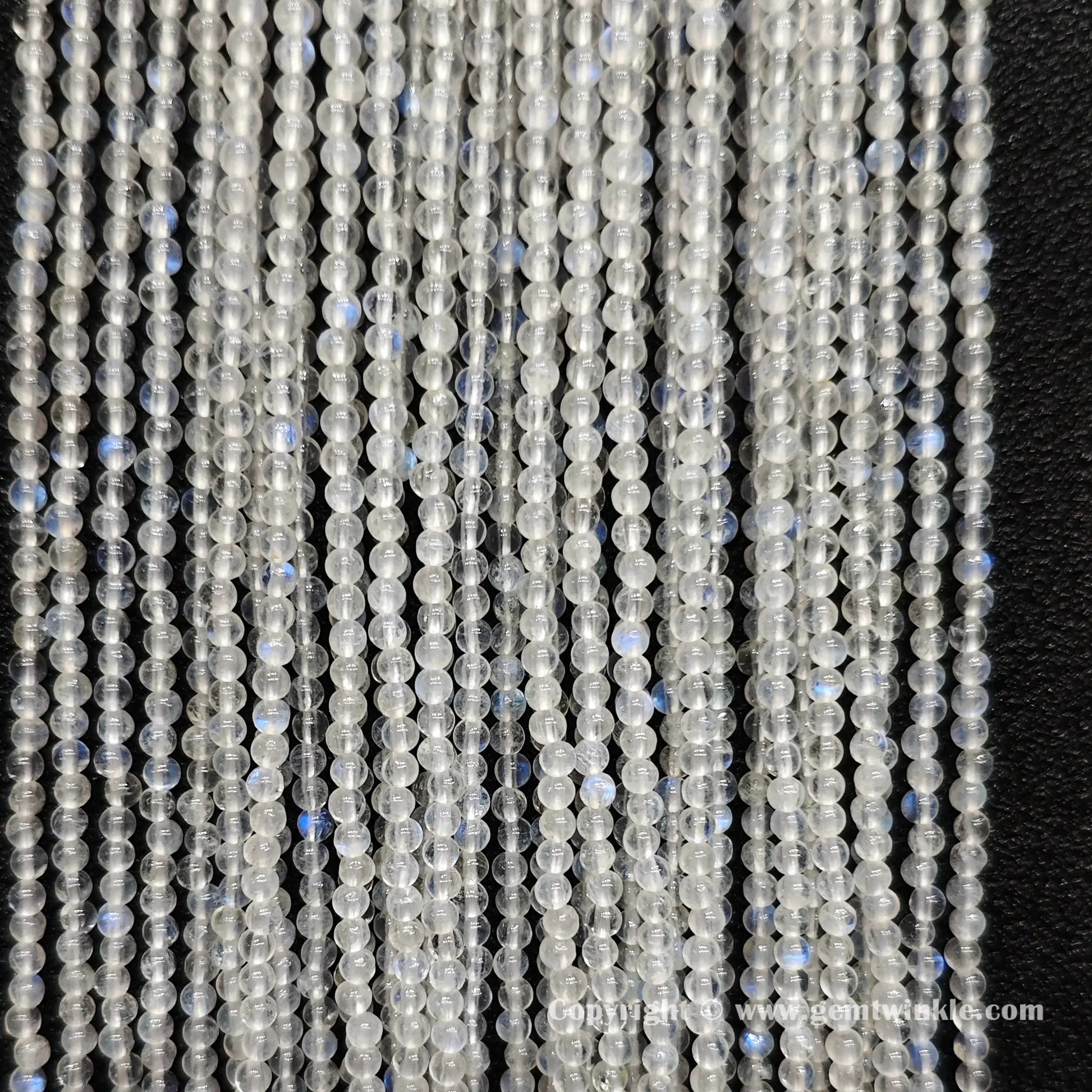 Perspective view of 2mm blue flash moonstone round seed beads displaying micro polished finish