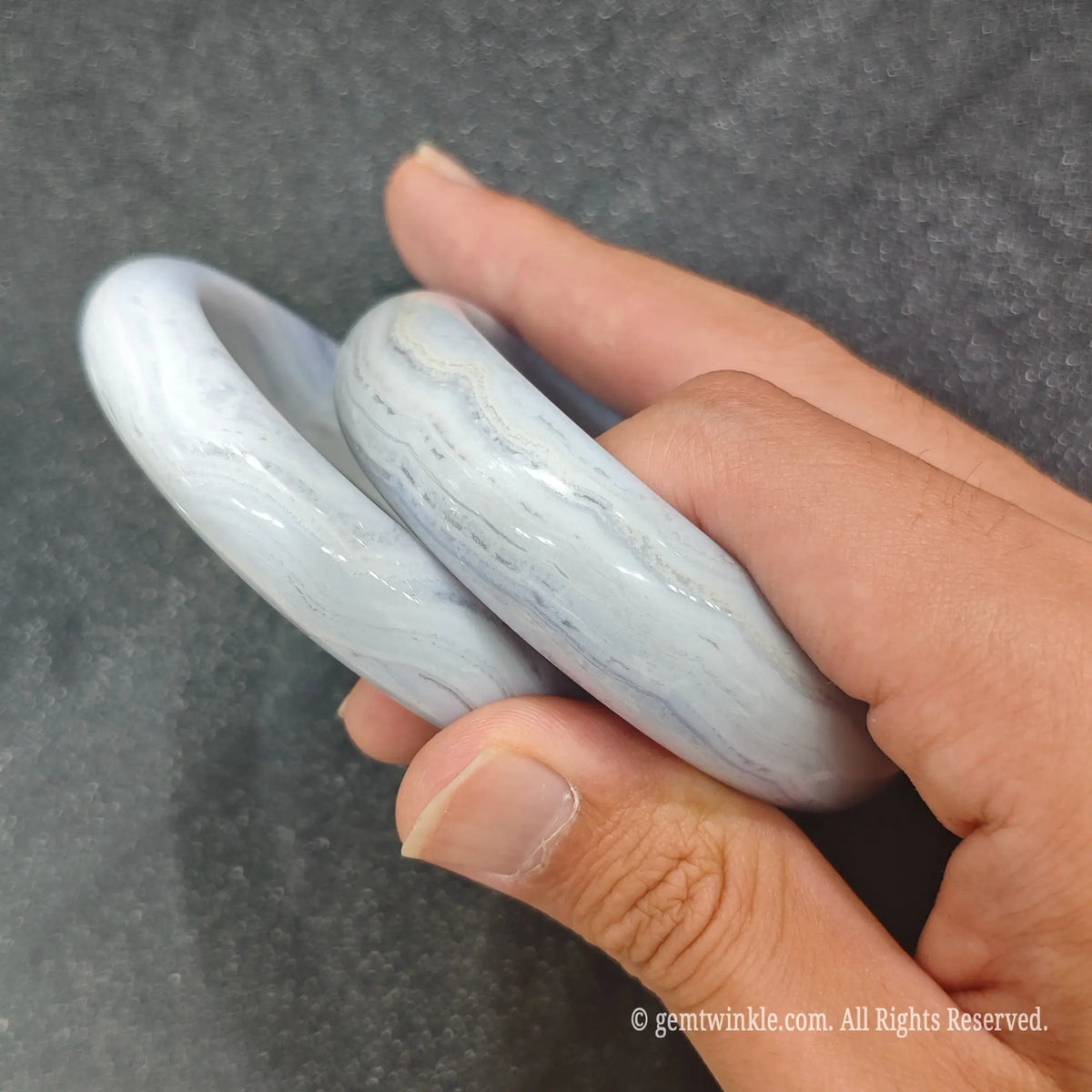 Pair of authentic carved Blue Lace Agate bangles showing soft pastel blue quartz translucency