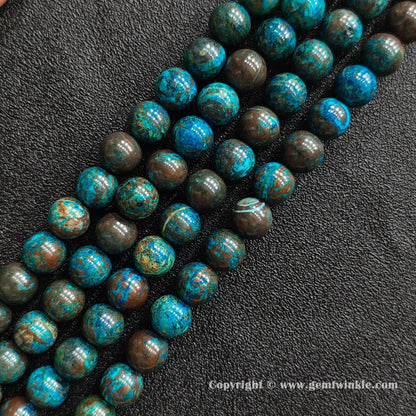 Angled view of blue phoenix stone round bead strands laid parallel on dark textured surface