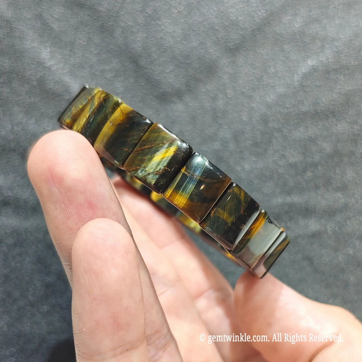 Side view of a blue yellow tiger eye bar cut band showcasing dual color light reflection across rectangular beads