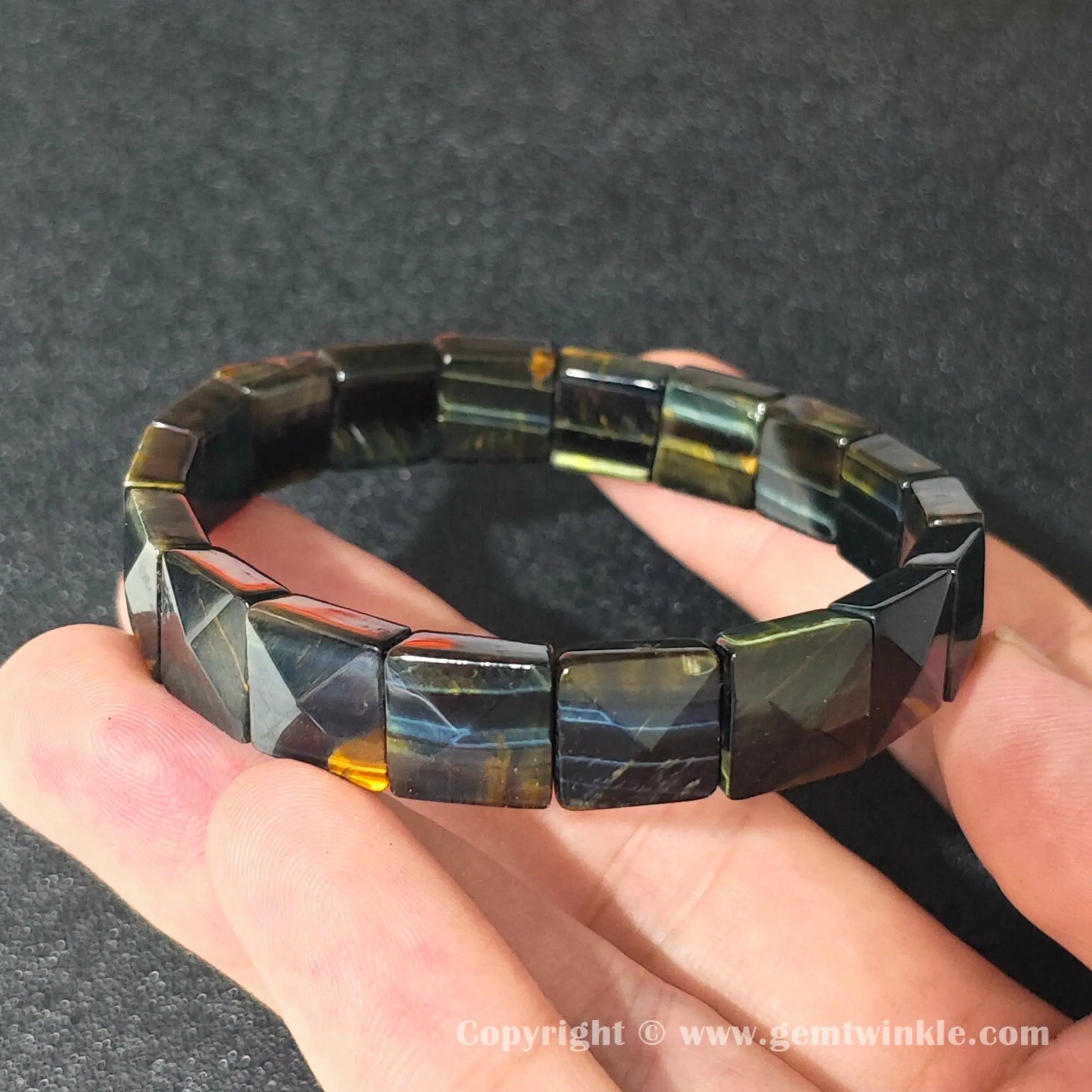 blue hawks eye curved plate bracelet resting on fingers displaying smooth machine polished surface