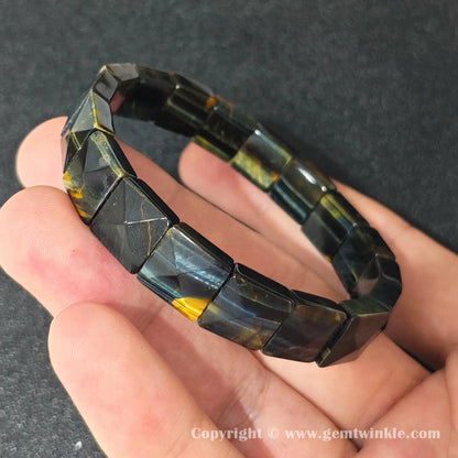 side profile view of machine polished blue tigers eye cuff bracelet held over palm