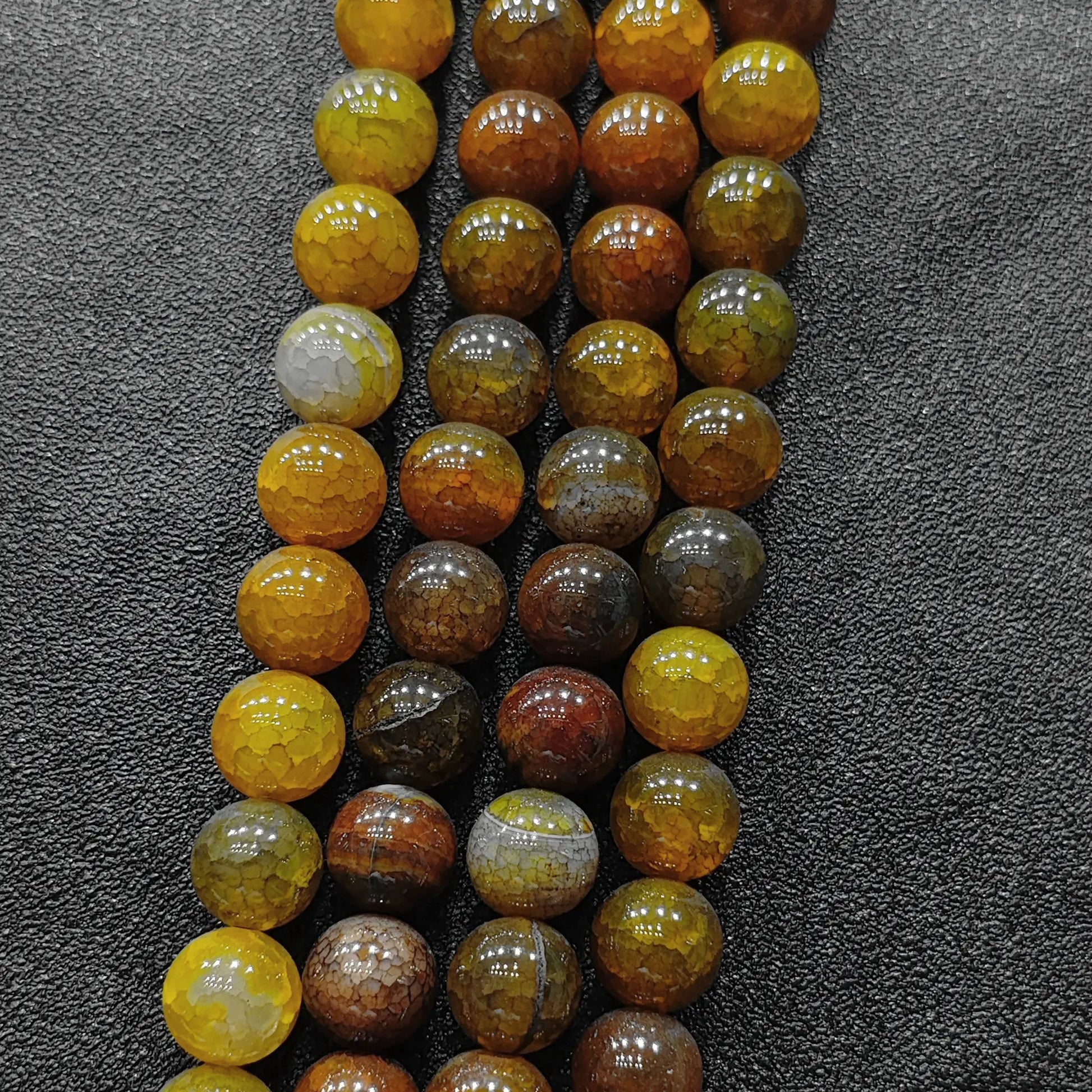 Arranged rows of bohemian yellow dragon vein agate beads from 4mm to 14mm for boutique size grid choice