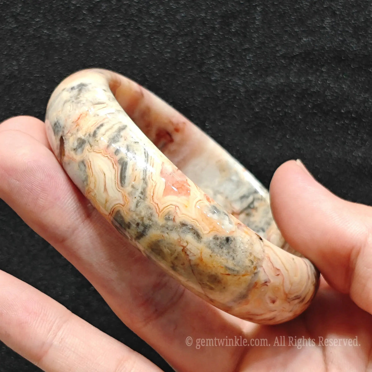 side view demonstrating intricate cream and orange layers of agate bangle