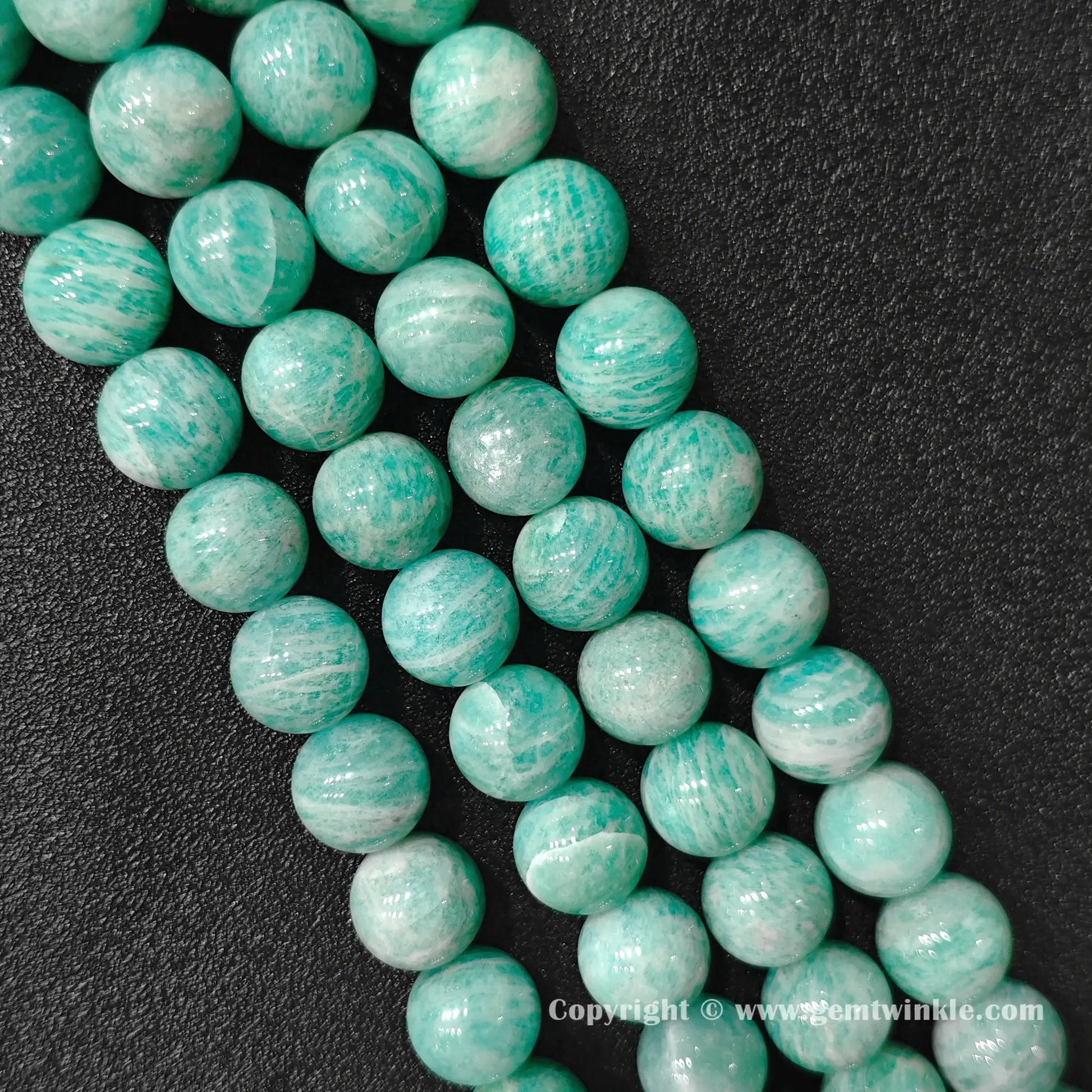 Angled view of natural Grade B amazonite 13-15mm large bead strands displaying polished texture