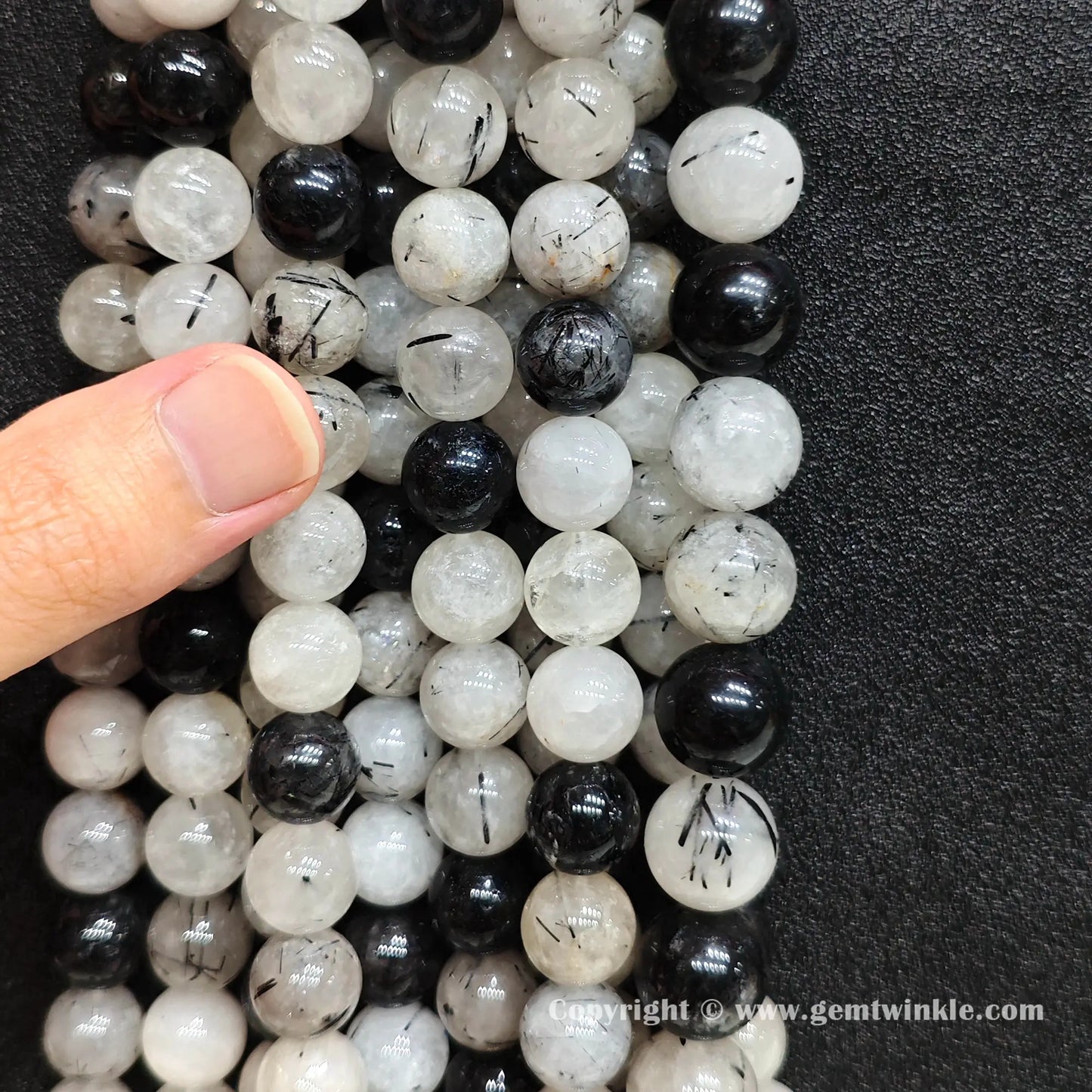 Multiple strands of C grade commercial black quartz rutilated beads hung together showing raw earth-mined heavy fractures for independent makers