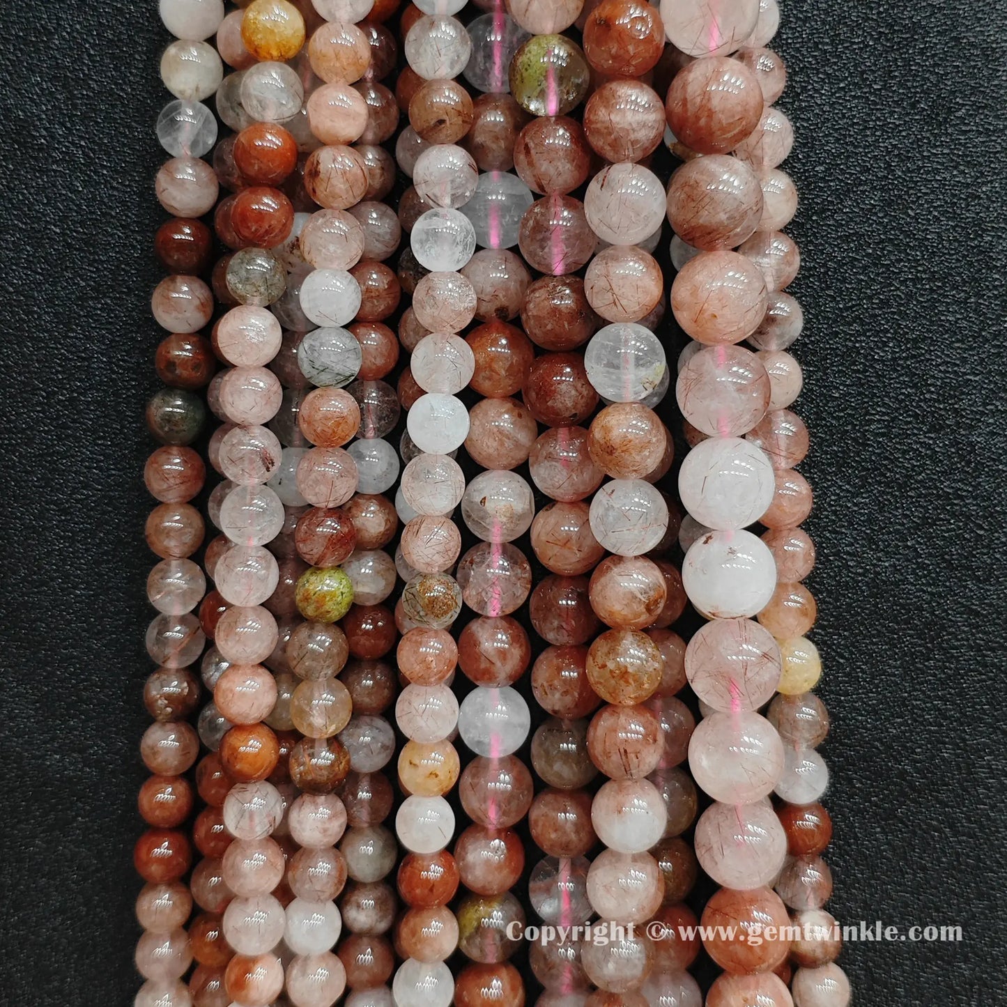 Multiple strands of raw earth-mined red rutilated quartz beads hung together showing natural color gradients and crystal clarity for small shop owners