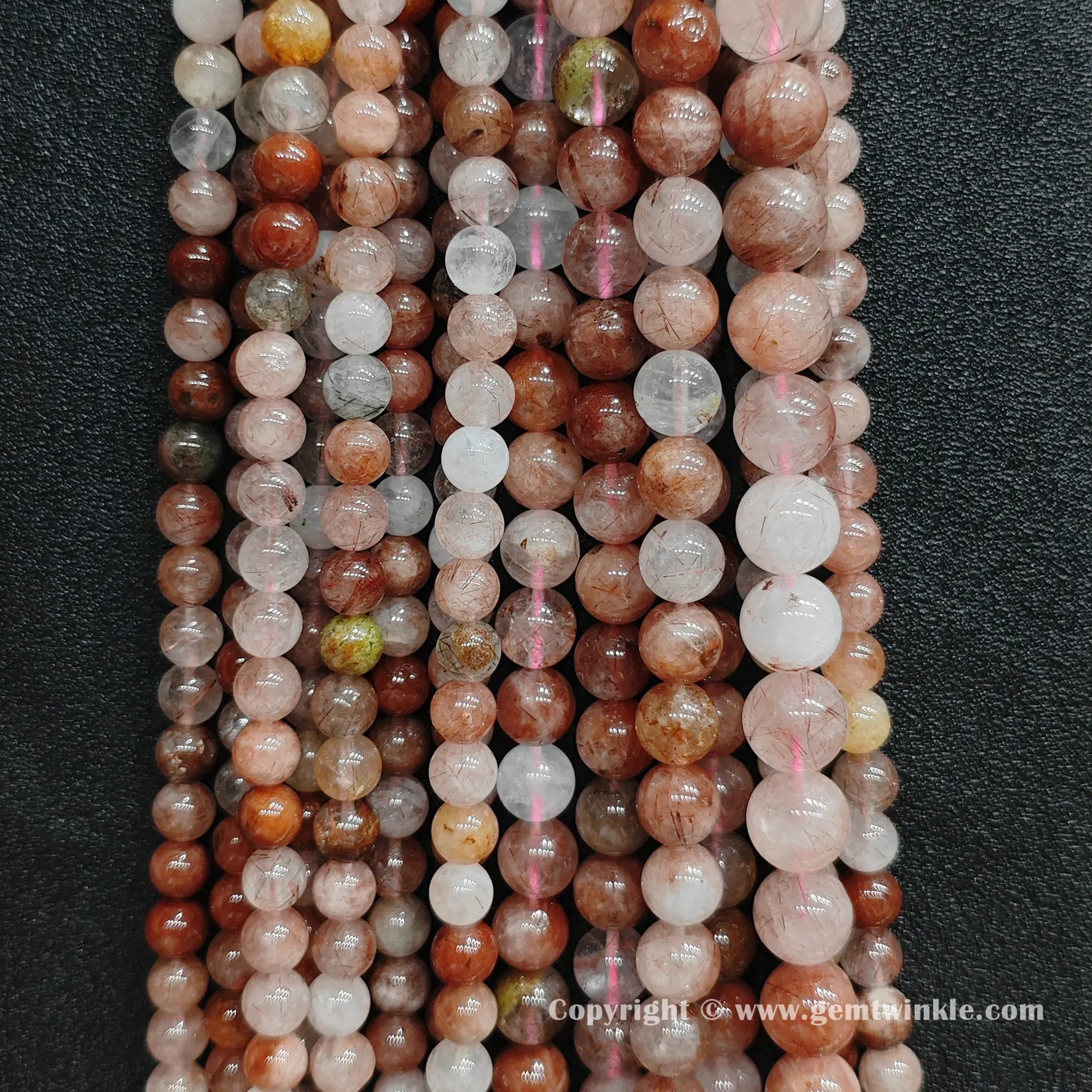 Multiple strands of raw earth-mined red rutilated quartz beads hung together showing natural color gradients and crystal clarity for small shop owners