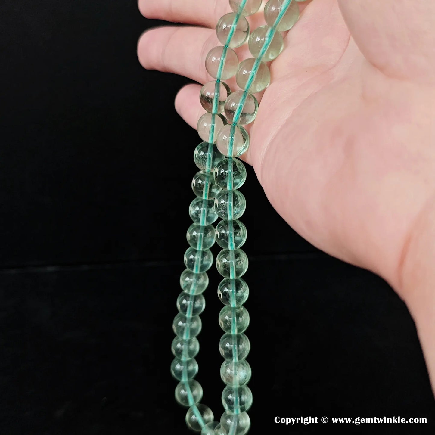 Natural green fluorite round loose bead strand hanging vertically for bulk supply and jewelry manufacturing