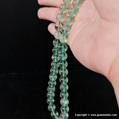 Natural green fluorite round loose bead strand hanging vertically for bulk supply and jewelry manufacturing