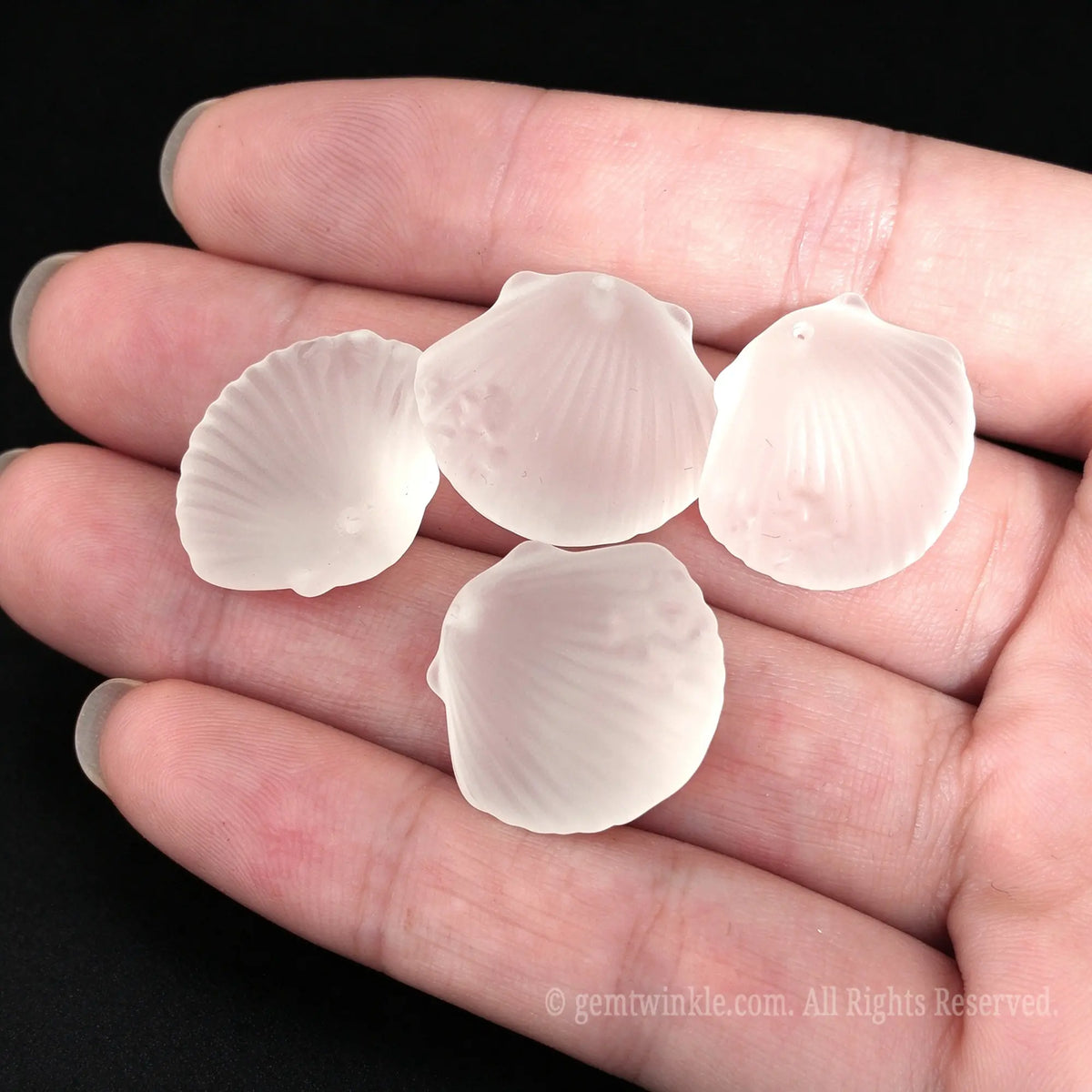 multiple matte white gemstone shell charms on palm