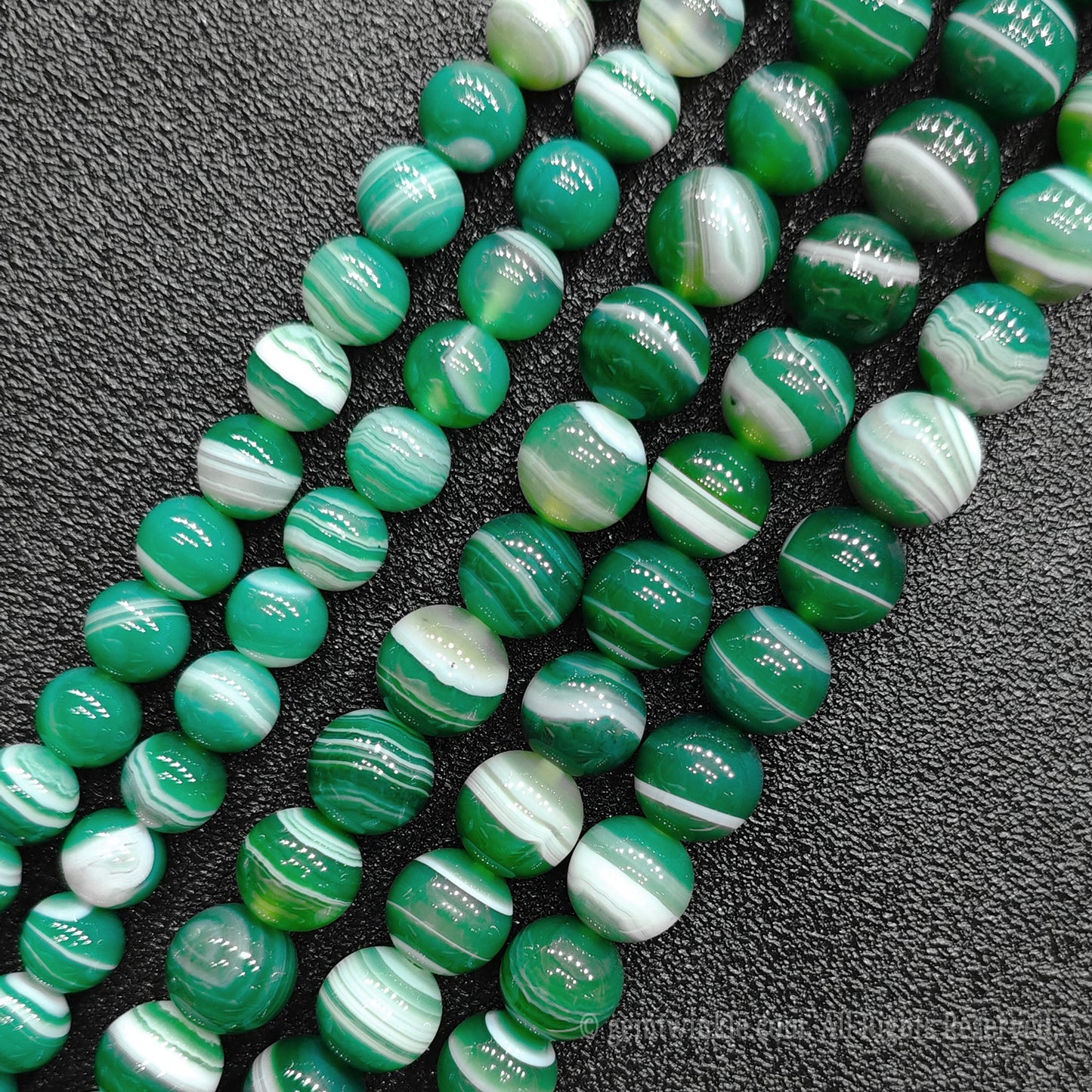 Close up view of natural green banded agate strands showing beautiful concentric ribbons and transparent layers for handmade bracelet design