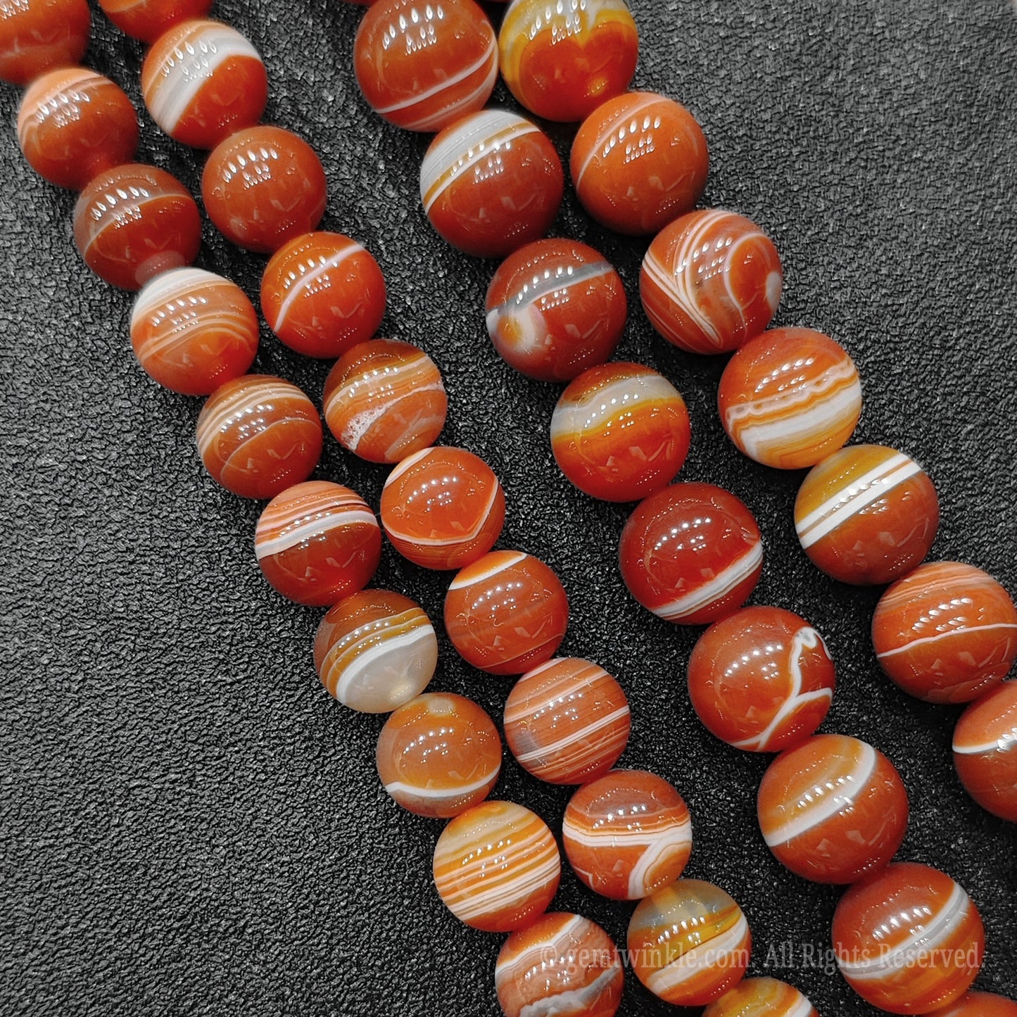 Close up view of natural red banded agate strands showing beautiful concentric ribbons and transparent layers for handmade bracelet design