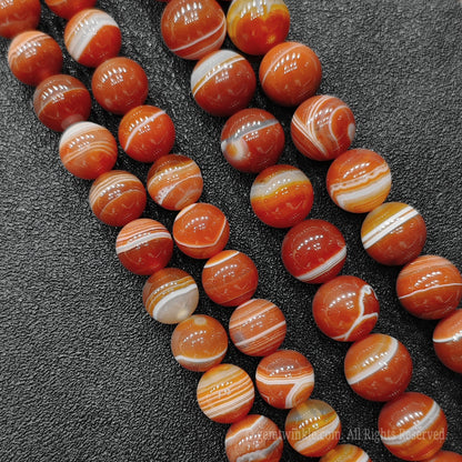 Close up view of natural red banded agate strands showing beautiful concentric ribbons and transparent layers for handmade bracelet design