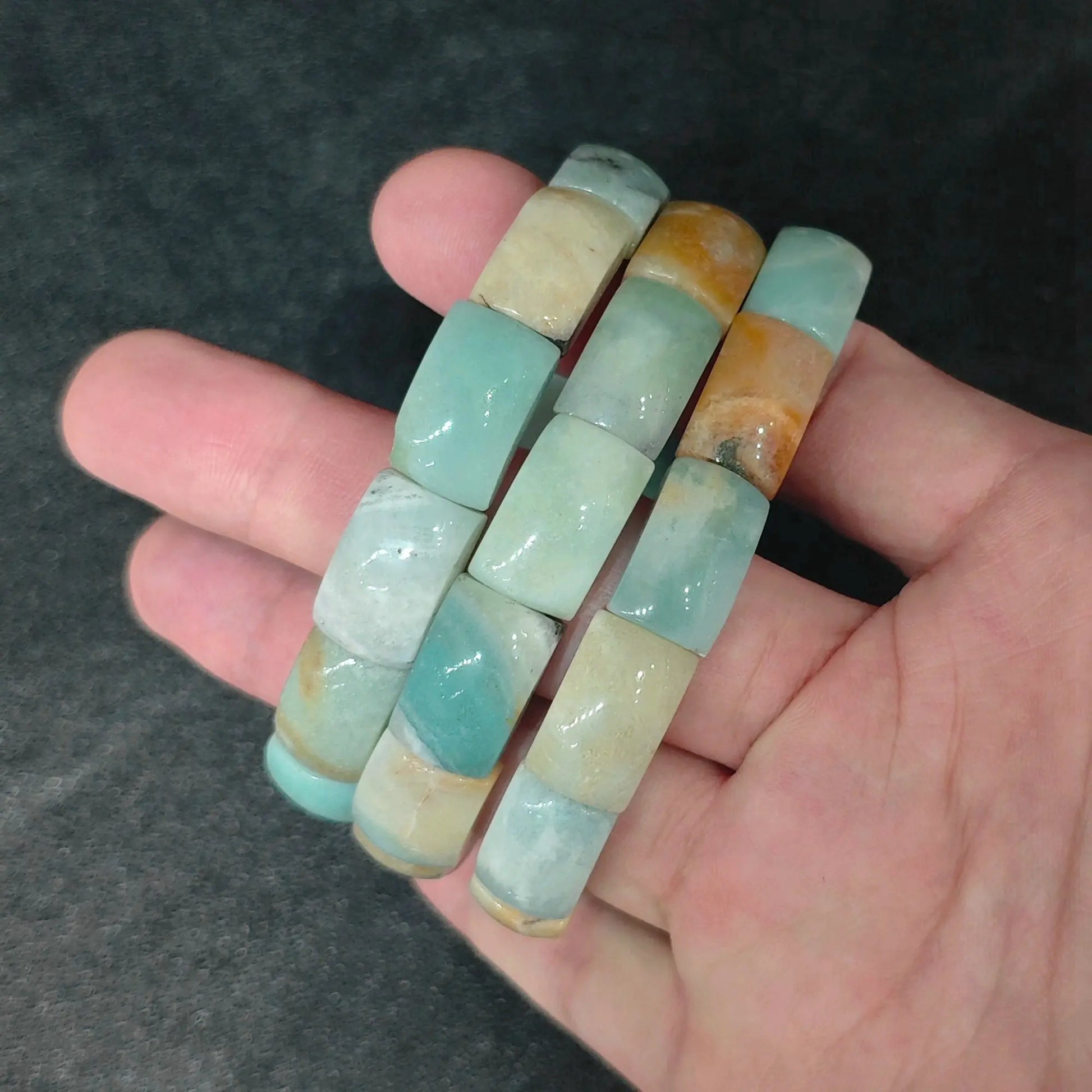 Main handheld view of natural Caribbean Calcite barrel bead stretch bracelets showing seafoam blue and sandy brown beads