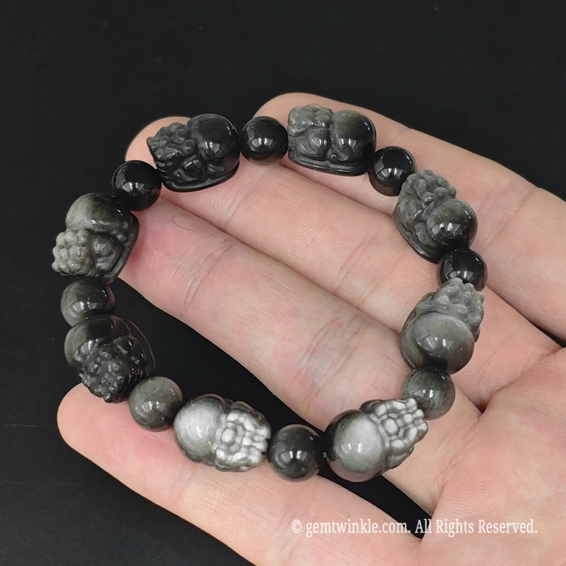 14mm carved silver sheen obsidian pixiu stretch bracelet displayed in open hand