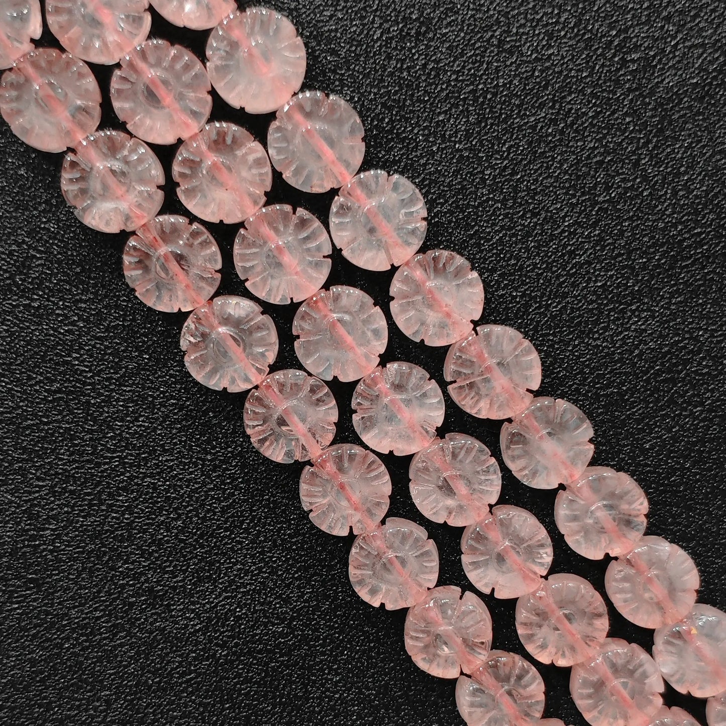 Macro closeup of carved natural rose quartz plum blossom flower beads showing smooth polish