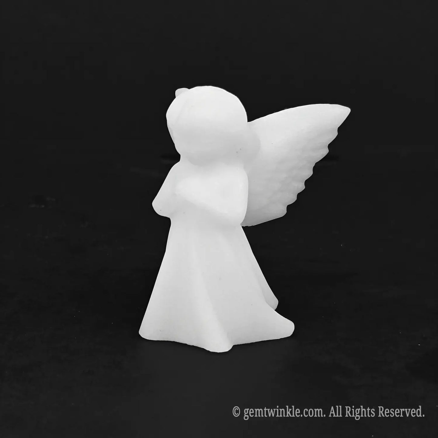Angled view of a pocket sized carved white stone angel figurine suitable for baptism favors and wedding gifts