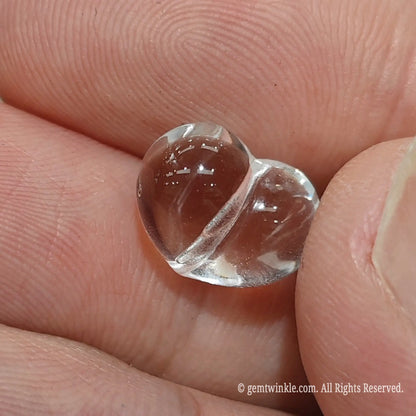 Carved 3d clear quartz heart bead side angle view displaying ice clean crystal transparency and light refraction