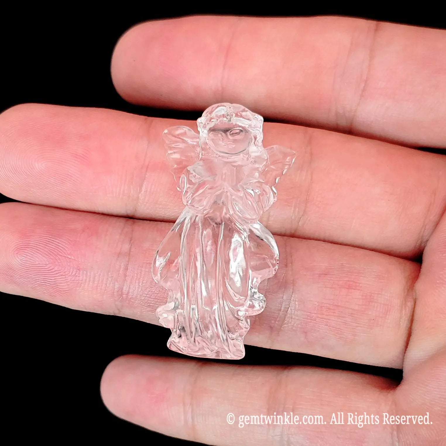 Clear quartz carved praying angel figurine resting on open palm demonstrating hand size ratio