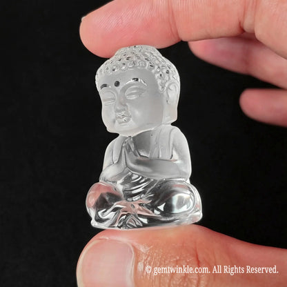 Three-quarter angle view of clear quartz buddha statue held in hand highlighting glass-like clarity