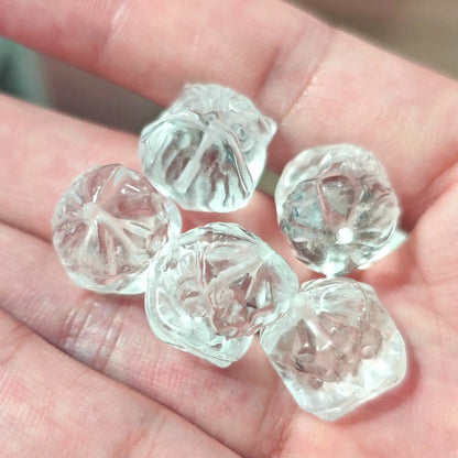Carved quartz foo dog beads in hand highlighting detailed facial features and high transparency