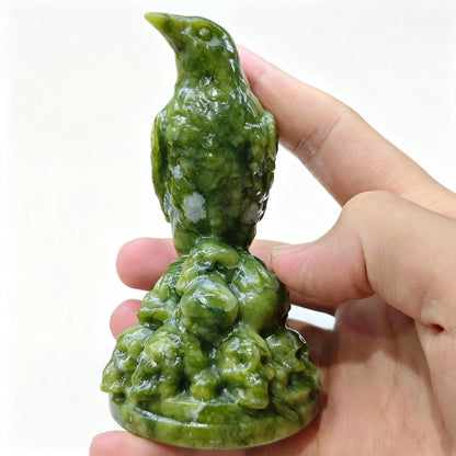 Carved serpentine raven statue 10cm held in hand showing upright bird pose and skull pile base
