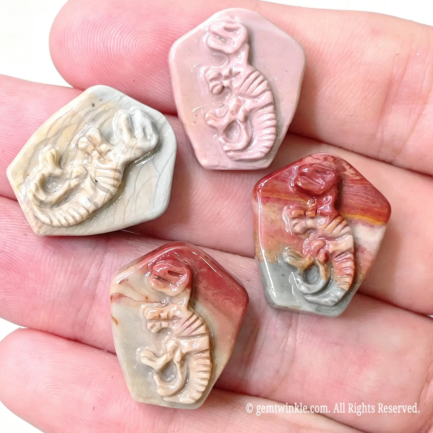 Assortment of carved Alashan desert agate T-Rex skeleton fossil relief stones for small shop inventory