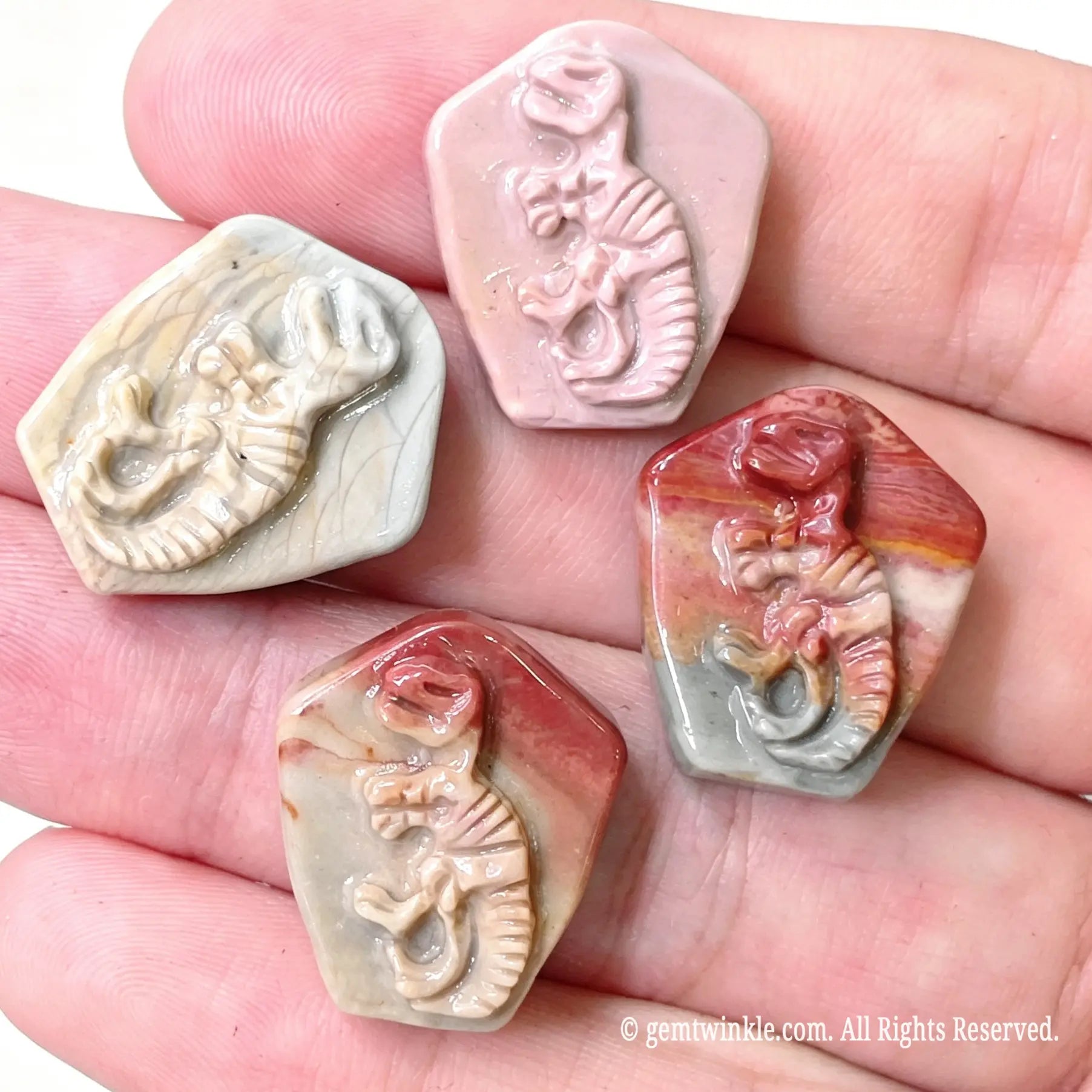 Assortment of carved Alashan desert agate T-Rex skeleton fossil relief stones for small shop inventory