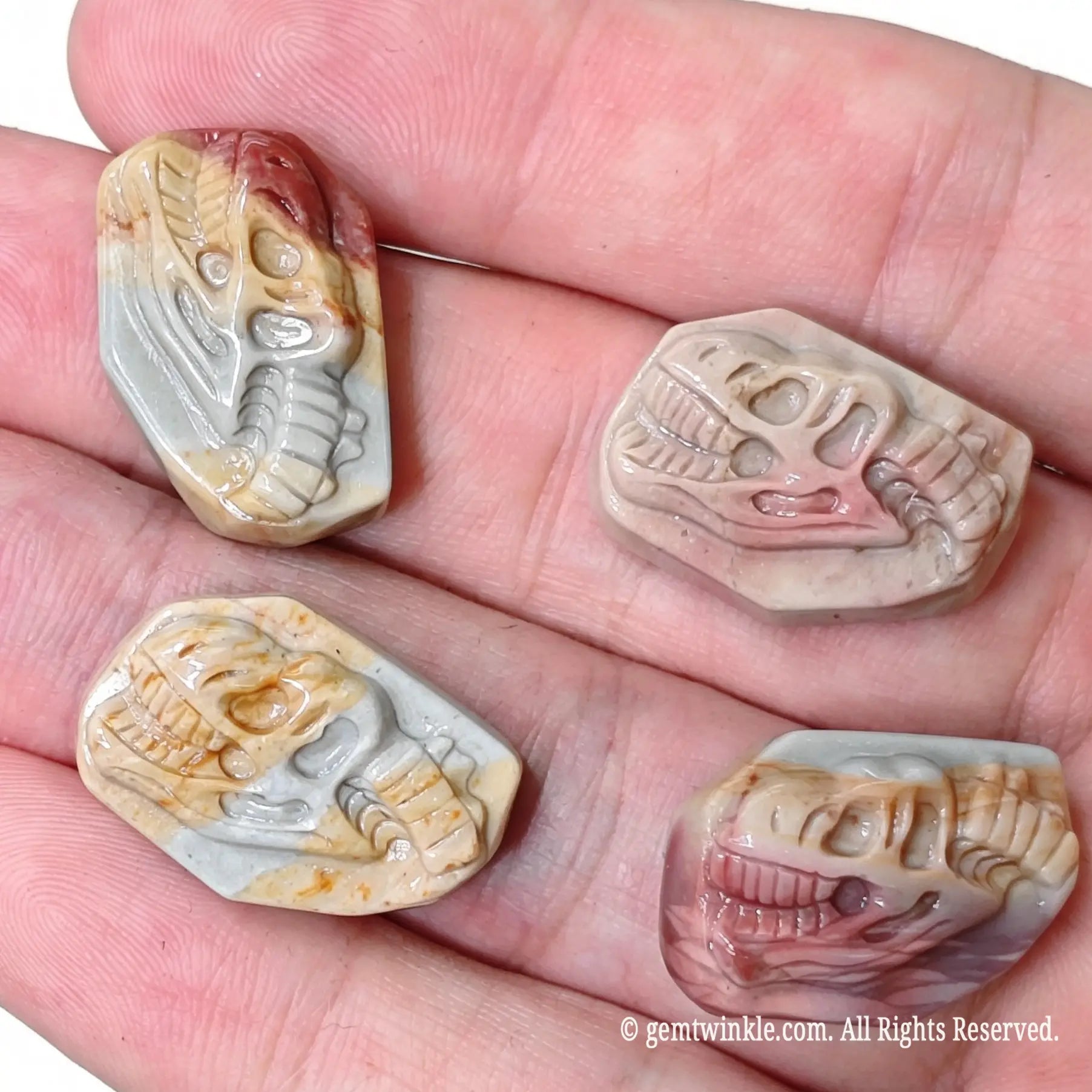 Assortment of carved Alashan desert agate T-Rex skull relief stones for small shop inventory