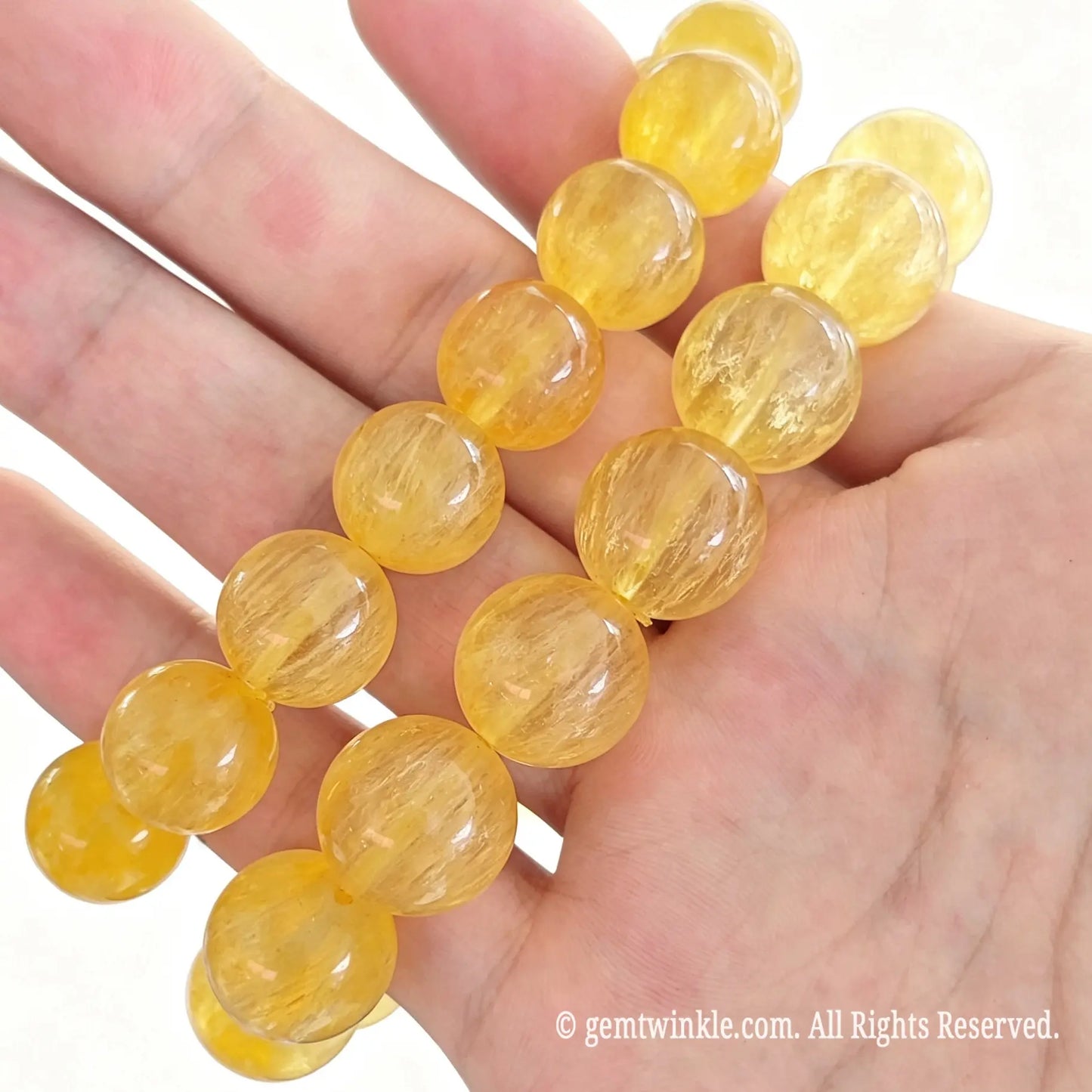 Yellow silk fluorite bead stretch bracelets displayed side by side across open hand highlighting bright golden yellow hues