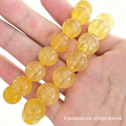 Yellow silk fluorite bead stretch bracelets displayed side by side across open hand highlighting bright golden yellow hues